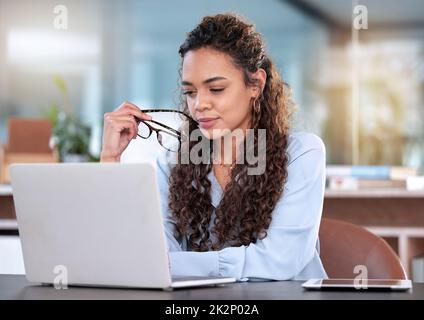 Ive ha avuto pensare con attenzione a questo. Scatto corto di una giovane donna d'affari attraente che guarda premuroso mentre lavora sul suo laptop in ufficio. Foto Stock