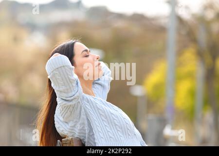 Donna rilassata seduta su panca riposante in un parco Foto Stock