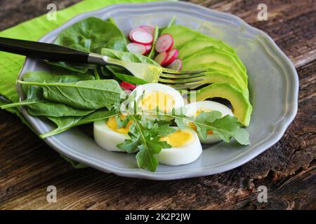 La prima colazione con insalata di ravanelli, uovo sodo e mescolare le foglie di lattuga, spinaci. Sfondo di cibo. Vista superiore Foto Stock