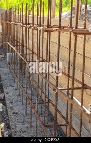 Costruzione di una fondazione a nastro, reggiatura di rinforzo, casseforme sullo sfondo Foto Stock