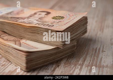 Pila di banconote thailandesi baht su sfondo di legno, business risparmio finanziario concetto di investimento. Foto Stock