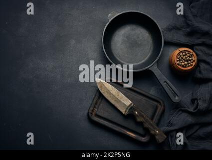 Padella rotonda vuota in ghisa con manico in legno sul tavolo nero, vista dall'alto Foto Stock