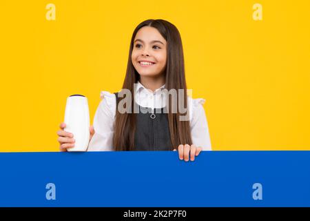 Bambina teen con bottiglia di shampoo o gel doccia isolato su sfondo giallo. Prodotti cosmetici per bambini. Faccia felice della ragazza, positiva e sorridente Foto Stock