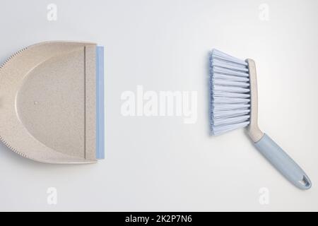 Set di sessola per il cestino dei rifiuti. Paletta in plastica grigia e blu e spazzola a mano su sfondo bianco. Pulizia della casa, chores concetto domestico. Vista dall'alto, spazio di copia Foto Stock