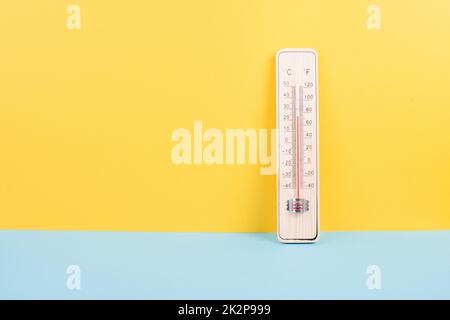 Termometro su sfondo giallo e blu, misurazione della temperatura, previsioni meteorologiche, riscaldamento globale e discussione sull'ambiente, stagione estiva Foto Stock