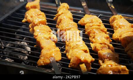 Shashlik - tradizionale barbecue Georgiano. Primo piano di carne cruda arrostita marinata barbecue shish kebab shashlik su spiedini di metallo d'acciaio giacendo griglia fuoco brazier con carbone. Fare barbecue Foto Stock