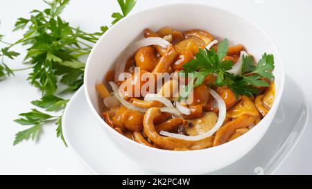 Funghi marinati a base di miele selvatico Armillaria mellea funghi con spezie e cipolle nel recipiente. Foto Stock