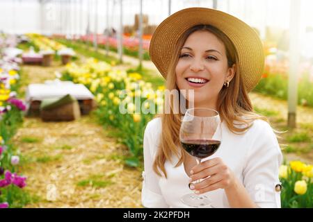 Ritratto di giovane donna felice che tiene il bicchiere di vino guardando lateralmente e sorridente. Spazio di copia. Foto Stock