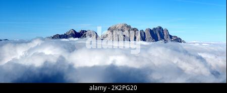 Mangart montagna nelle nuvole, Alpi Giulie, Slovenia. Mattina nebbie e nebbia intorno Mangart picco roccioso di montagna Foto Stock