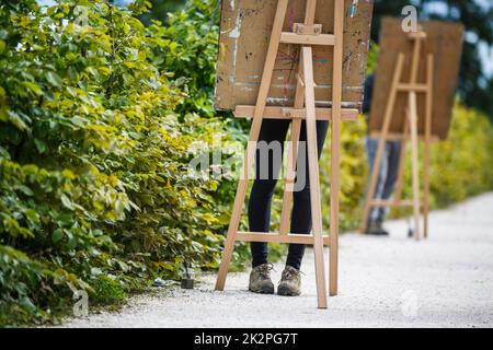 Palette e pennello in mani d'artista. L'artista dipinge un'immagine a olio con un pennello in primo piano nella tavolozza delle mani. Pittura artista che tiene in mano la tavolozza e il pennello. Pennello per artisti con tavolozza. Foto Stock