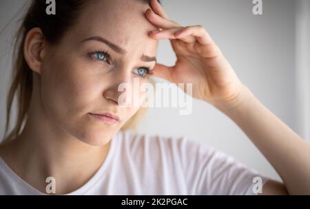 Ansiosa, preoccupata, stressata giovane donna che guarda penosa, ponderante, profonda nei pensieri. Foto Stock