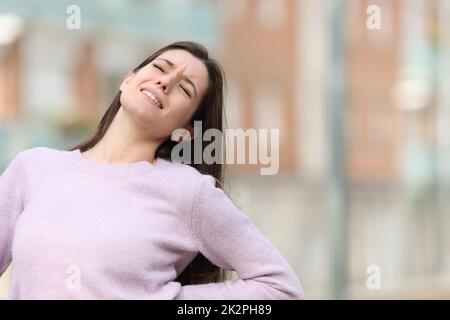 L'adolescente si lamentava del mal di schiena per strada Foto Stock