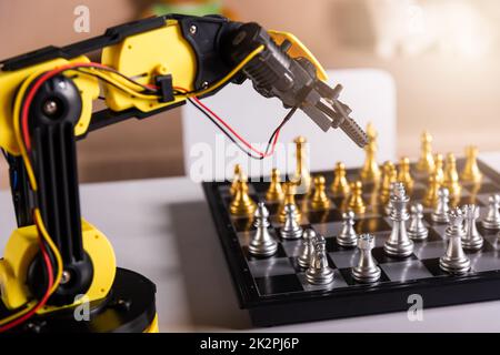 Primo piano braccio robot giallo giocare a scacchi in movimento sulla scacchiera Foto Stock