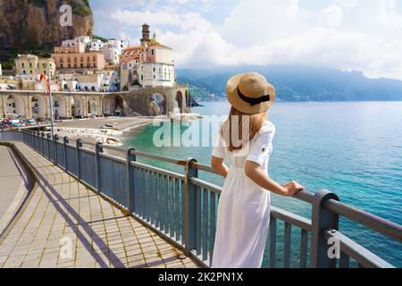 Vacanze in Costiera Amalfitana. Vista posteriore della bella ragazza di moda godendo la vista del villaggio di Atrani sulla Costiera Amalfitana. Vacanze estive in Italia. Foto Stock