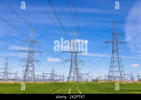 Torri elettriche ad alta tensione, linee elettriche di trasmissione, cavi su trasformatori e sottostazione di distribuzione Foto Stock