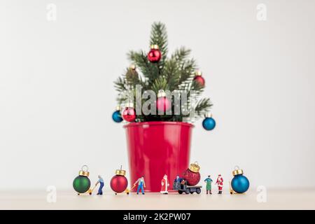 Persone in miniatura che decorano l'albero di Natale gigante Foto Stock