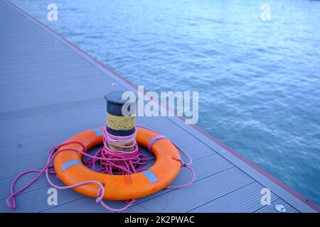 Anello di Lifebuoy sull'ormeggio vicino al bullard con vista mare all'aperto Foto Stock