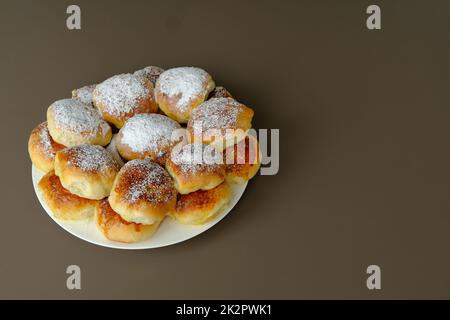 Gnocchi o torte di mele fatti in casa in vecchio stile su un piatto bianco e sfondo marrone. Cotto secondo ricetta Ucraina. Foto Stock