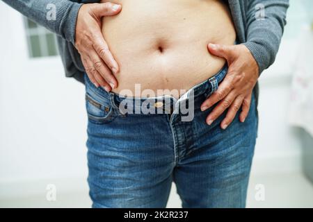 Donna asiatica mostra pancia grasso grande dimensione sovrappeso e obesità in ufficio. Foto Stock
