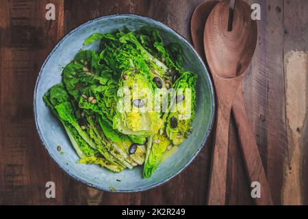 Ciotola di insalata verde mista con semi su sfondo di legno Foto Stock