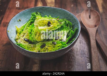 Ciotola di insalata verde mista con semi su sfondo di legno Foto Stock