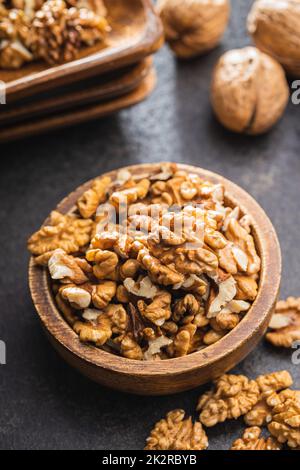 Nocciole pelate in ciotola di legno su tavolo nero. Foto Stock