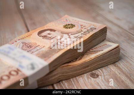 Pila di banconote thailandesi baht su sfondo di legno, business risparmio finanziario concetto di investimento. Foto Stock