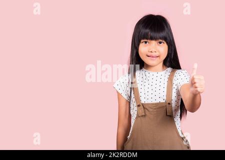 Capretto asiatico piccolo 10 anni che mostra i pollici in su Foto Stock