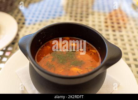 Zuppa di pesce con verdure in recipiente in ceramica Foto Stock