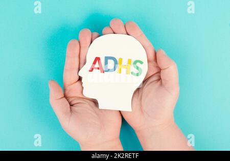 Mani che tengono una testa con la parola tedesca ADHS che significa disturbo da deficit di attenzione iperattività, sintomo ADHD, salute mentale Foto Stock