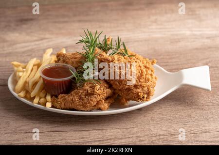 Pollo fritto e patata con foglia di rosmarino, cibo spazzatura ad alto contenuto calorico servito su piatto bianco Foto Stock