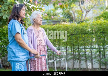 Aiuto del medico e cura Asian anziani o anziani donna vecchia uso walker con la salute forte mentre camminando al parco in felice vacanza fresca. Foto Stock