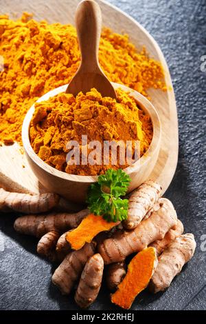 Composizione con una ciotola di curcuma macinato e il suo rizoma fresco Foto Stock