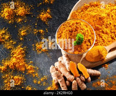 Composizione con una ciotola di curcuma macinato e il suo rizoma fresco Foto Stock