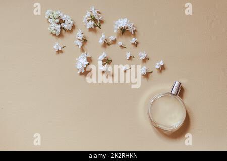 concetto di profumeria e profumo floreale. elegante bottiglia di profumo con spray di fiori di lilla su sfondo beige. piatto creativo e alla moda con spazio per il testo. Foto Stock