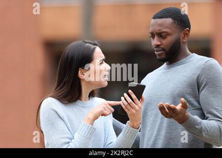 Donna che chiede spiegazioni sul testo del telefono a un uomo Foto Stock