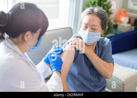 Donna anziana che riceve il vaccino. Medico che vaccina un paziente anziano contro l'influenza, il covid-19, la polmonite o il coronavirus. Foto Stock