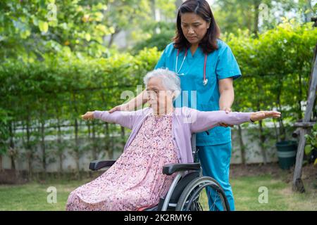 Aiuto medico Asiatico anziano o anziano donna anziana esercizio paziente su sedia a rotelle con felice nel parco. Foto Stock