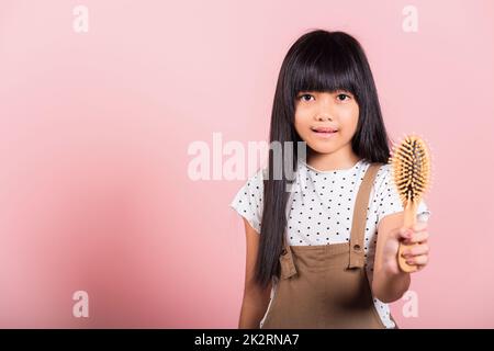 Bambino asiatico 10 anni tenere pettine spazzolarla unruly tocca i suoi lunghi capelli neri Foto Stock