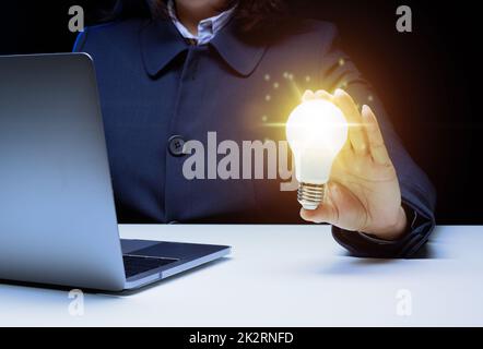 La mano di una donna tiene una lampadina, il concetto di innovazione attraverso le idee e l'ispirazione. Sviluppo aziendale attraverso la ricerca di nuove aree di attività, ottimizzazione Foto Stock