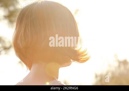 Il sole che i capelli della donna si voltarono indietro Foto Stock