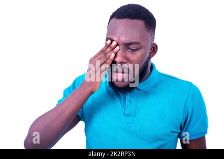 ritratto di un giovane triste che indossa una t-shirt blu, toccando l'occhio con la mano. Foto Stock
