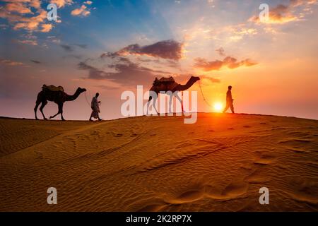 Camaleatori indiani driver cammello con silhouette cammello in dune al tramonto. Jaisalmer, Rajasthan, India Foto Stock