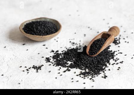 Cucchiaio di spezie indiane semi di cumino nero (nigella sativa o kalonji) su tavola bianca primo piano Foto Stock