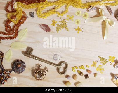 Gioielli gialli e marroni e decorazioni con chiave in ottone d'epoca sulla tavola in legno Foto Stock