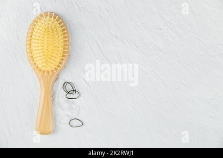 Un pettine massaggiatore per capelli in legno e piccole fasce in gomma si trovano su uno sfondo bianco. Foto Stock