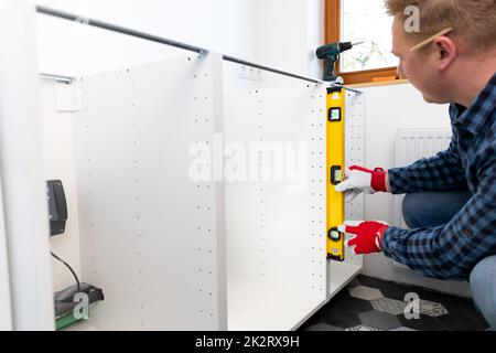 Miglioramento della casa. Handyman con livellatore installare nuovo piano di lavoro in cucina recentemente ristrutturato. Foto Stock