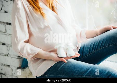 ragazza incinta dai capelli rossi in una blusa leggera e jeans blu Foto Stock