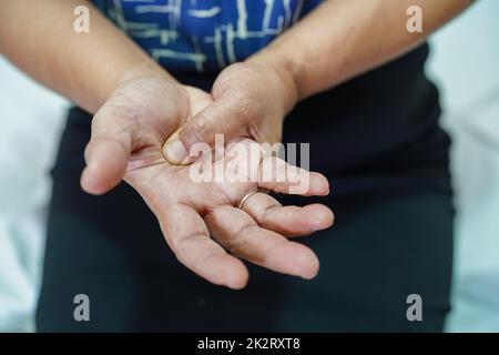 La donna anziana asiatica le fa male la mano e il dito, la tenosinovite di De Quervain. Foto Stock