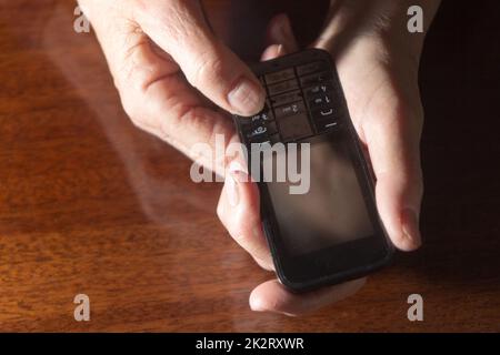 Le mani della vecchia donna sul telefono cellulare retrò Foto Stock